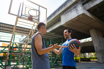 Fototapeta na wymiar Caucasian man basketball players celebrating while win streetball match with his friends at outdoors court under highway in the city. Fair game sport competition and outdoor sport training concept.