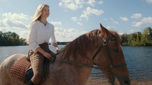 Female rider enjoying strolling along lavish fall landscape. Close-up of a blonde-haired woman riding on a horseback. High quality 4k footage