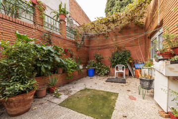 Interior patio with exposed clay bricks, pots of the same material and many plants in individual pots