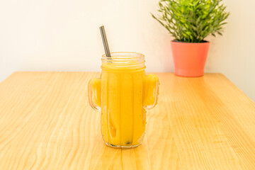 A ripe pineapple smoothie in a glass bowl on a pine wood table