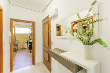 Hall of a house with armored door, wooden sideboard and mirror with white wooden frame