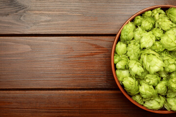 Bowl with fresh green hops on wooden table, top view. Space for text