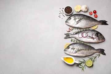 Flat lay composition with fresh raw dorado fish and ingredients on light grey table, space for text