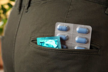 Jeans with pills and condom in pocket, closeup. Potency problem