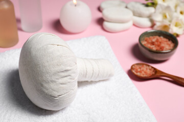 Herbal massage bag and other spa products on pink background, closeup. Space for text