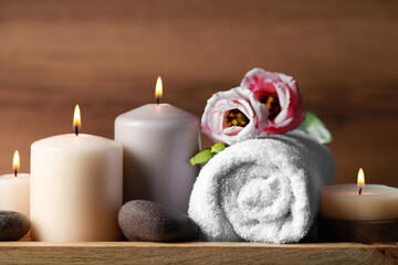 Fototapeta na wymiar Beautiful composition with spa stones, flowers and burning candles on wooden table