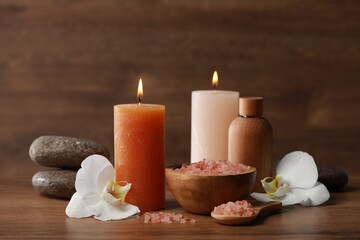 Fototapeta na wymiar Beautiful spa composition with sea salt, burning candles and flowers on wooden table