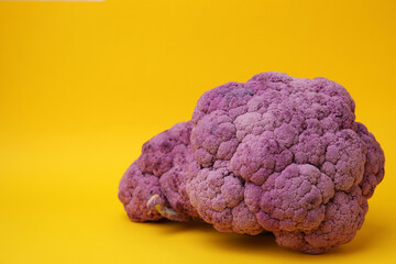 Fresh purple cauliflowers on yellow background. Space for text