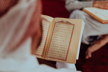 A group of Muslims reading the holy book of the Quran in a modern mosque during the Muslim holiday...