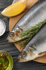 Delicious salted herrings and ingredients on black wooden table, flat lay
