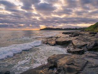 Fototapeta na wymiar Coastal Sunrise with Waves Crashing on Rocks