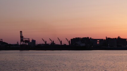 段々と赤く染まる空と対岸の工場のシルエット