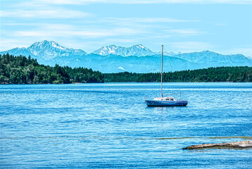 A sailboat rests in a secluded harbor with mountains in the background