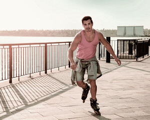 Handsome young man roller skating on pier near river, space for text