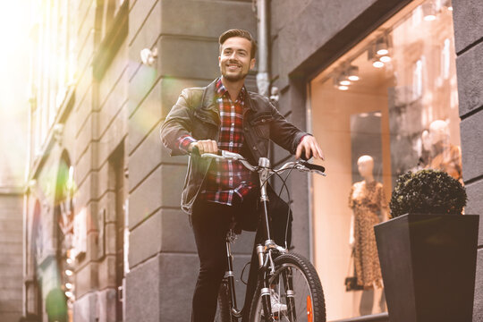 Handsome Happy Man Riding Bicycle In City On Sunny Day, Low Angle View