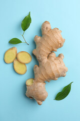 Fresh ginger with green leaves on pale light blue background, flat lay