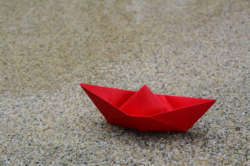 Beautiful red paper boat on sandy beach near water outdoors