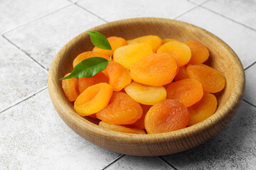 Wooden bowl of tasty apricots on white tiled table. Dried fruits