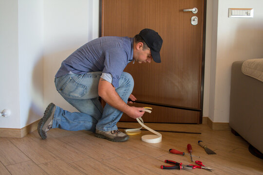 Image of a handyman installing seals and door sills to improve the thermal insulation of the house.
