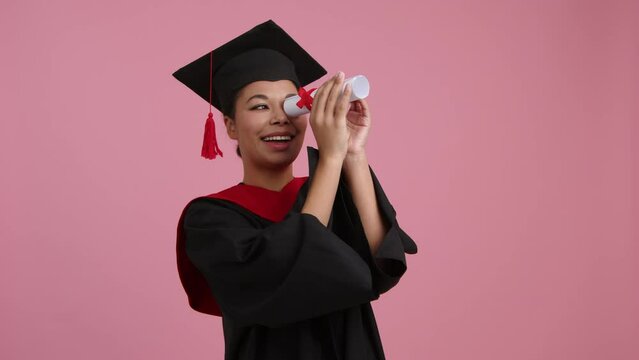 Portrait of a happy student with a master degree holding her diploma. Close-up shot of young woman in a gown and hat celebrating her achievement. High quality 4k footage