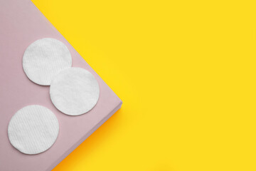 Soft clean cotton pads on yellow background, top view. Space for text