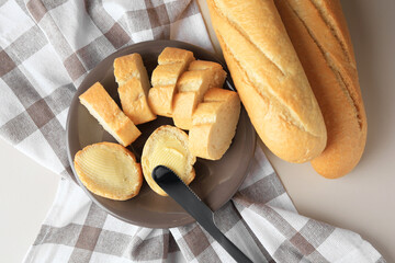 Whole and cut baguettes with fresh butter on table, flat lay