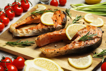 Tasty grilled salmon steaks and different ingredients on light grey table