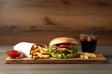 Delicious burger, soda drink and french fries served on wooden table
