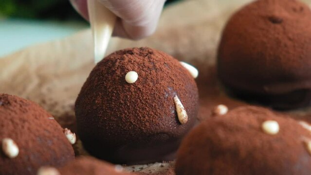 Glazed chocolate truffles on wooden background. Pouring white chocolate glaze on chocolate truffles. Domestic confectionery. Food dessert background. Bakery and pastry shop concept. cook cuts a potato