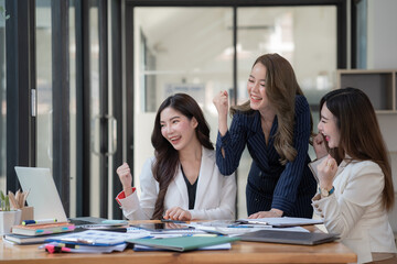 Fototapeta premium Female colleagues excited by an online win or business achievement, multiracial happy businesswomen celebrating victory by looking at a tablet computer screen watching cheering winning team.