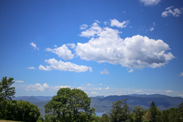 blue sky and clouds above green valley and lake