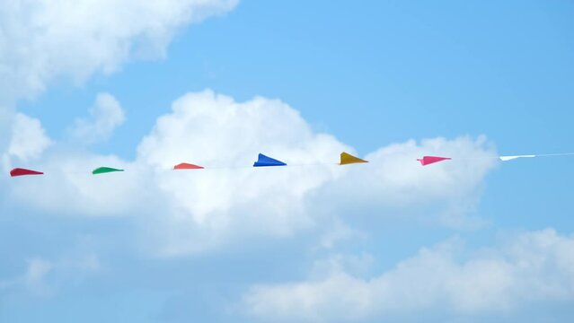 Colorful small flags in the sky. Waving small colorful flags hanging on the rope for holidays against blue sky.