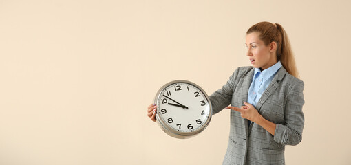 Shocked young businesswoman with clock on light background with space for text. Time management...