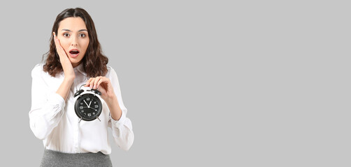Shocked businesswoman with alarm clock on grey background with space for text. Time management...