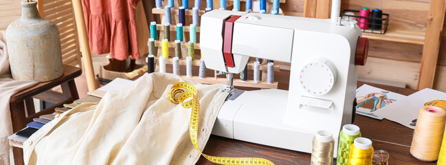 Tailor's workplace with sewing machine, clothes and supplies in atelier