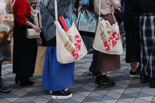 TOKYO, JAPAN - April 18, 2019: Fans with souvenir tote bags waiting to enter a concert by the band Arashi being held at Tokyo Dome.