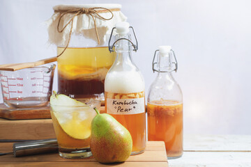 Homemade fermented raw Kombucha tea, healthy natural probiotic flavored drink, glass of Kombucha drink with pear fruits on white background