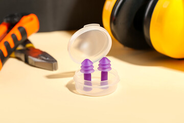 Fototapeta premium Plastic container with ear plugs on color background