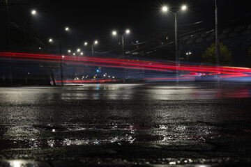 Wet road and glowing lights in illuminated city at night