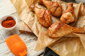 Tasty baked chicken legs on light wooden background, closeup