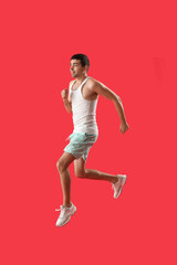 Fototapeta na wymiar Sporty young man jumping on red background
