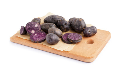 Wooden board of cut and whole raw purple potatoes on white background