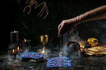 Fortune teller using pendulum and tarot cards to read future on dark background - Powered by Adobe