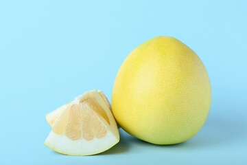 Whole and cut sweet ripe pomelo fruits on blue background