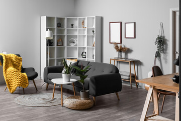 Interior of modern living room with black sofa, tables and shelving unit