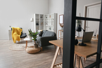 Interior of modern living room with black sofa, workplace and shelving unit