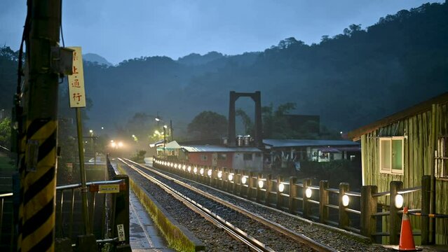 It's raining. The train is running through the mountains with the lights on. Sandiaoling Railway Station, New Taipei City, Taiwan. Translation "No Passing" by Chao Feng.