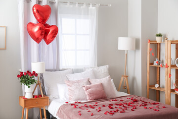 Interior of light bedroom decorated for Valentine's Day with roses, lamps and balloons