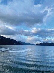 Fototapeta premium A sunny winter afternoon in Harrison Hot Springs, British Columbia, Canada. Blue sky, white cloudy, and beautiful reflection. Some waves and thin ice on the lake surface.