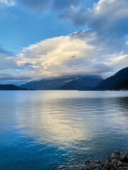 A sunny winter afternoon in Harrison Hot Springs, British Columbia, Canada. Blue sky, white cloudy, and beautiful reflection. Some waves and thin ice on the lake surface.